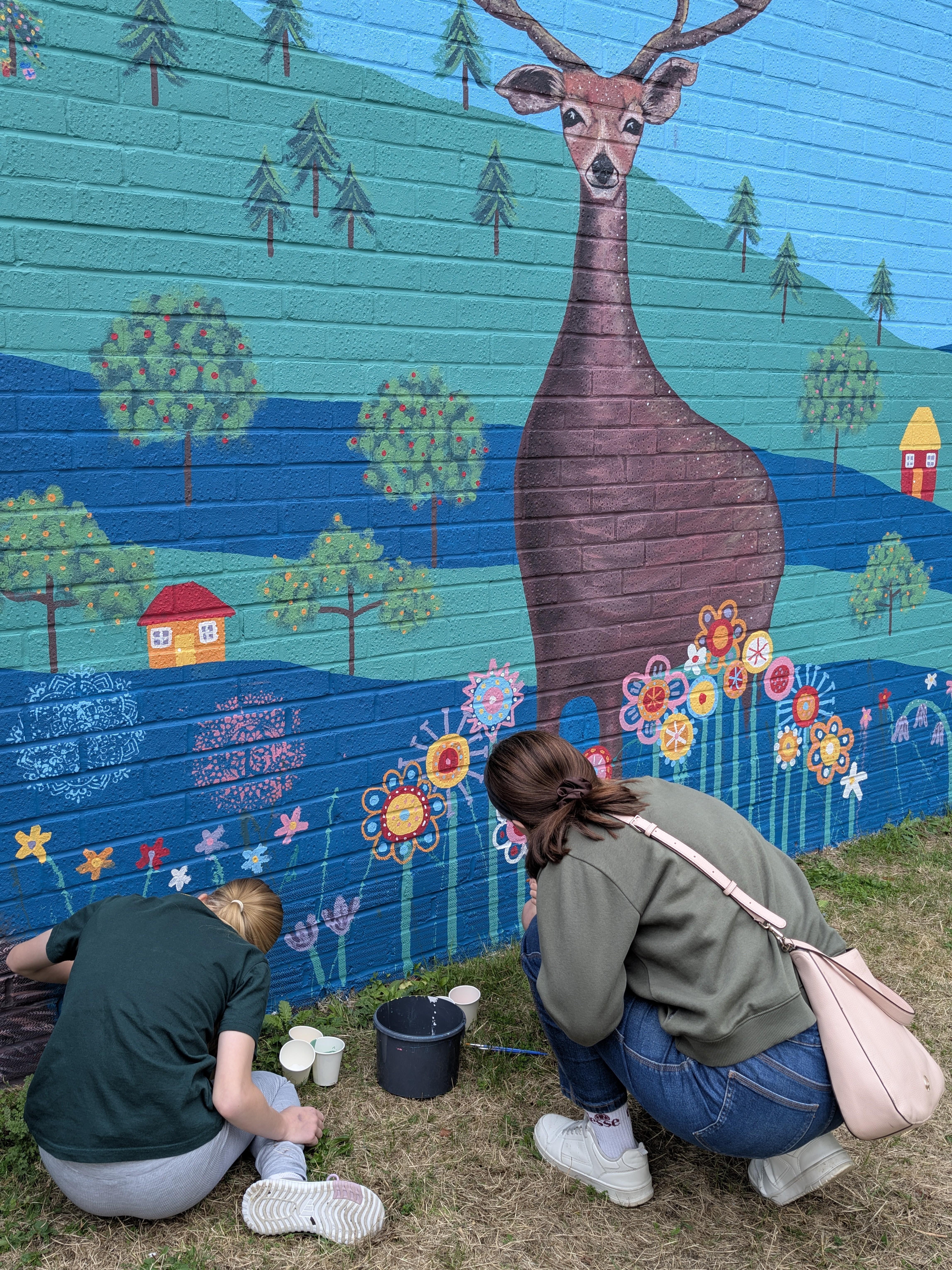 Resident painting alongside the central stag during the Wild & Wonder™ community mural experience by Janine Tonkin™