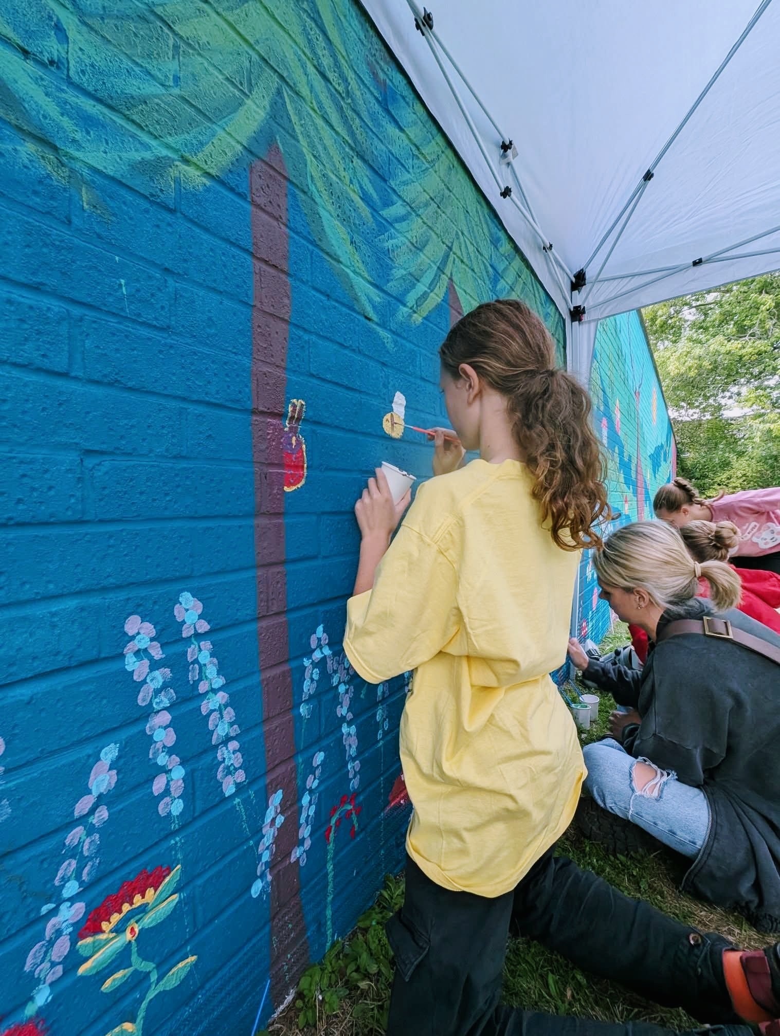 Young participant adding their own flower to the Wild & Wonder™ community mural by Janine Tonkin™