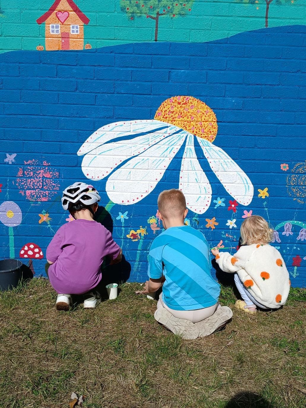 Young family painting flowers together during the Wild & Wonder™ community mural celebration by Janine Tonkin™