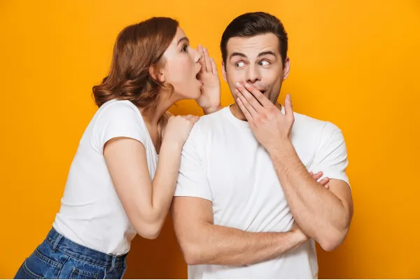 Person whispering into another person's ear, symbolizing behind-the-scenes conversations and communication during divorce.