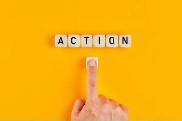 Hand pressing a letter tile to spell “ACTION” on a bright yellow background.