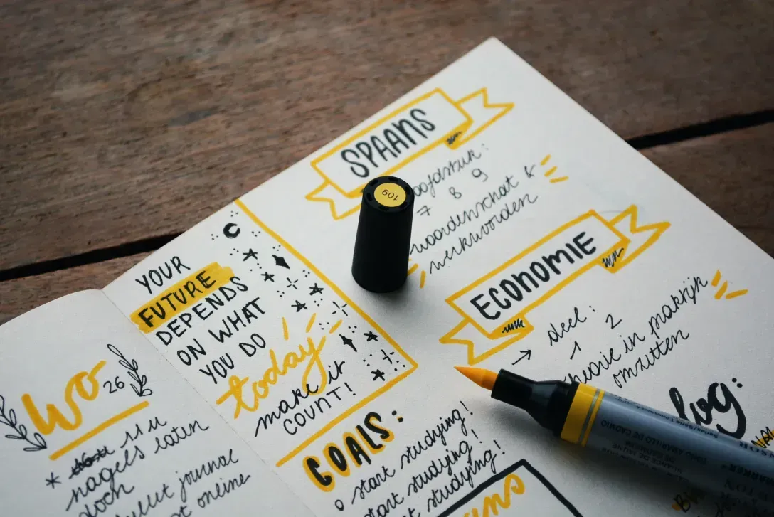 Open planner with handwritten goals, future planning notes, and financial headings on a wooden desk, representing strategic planning for the future.