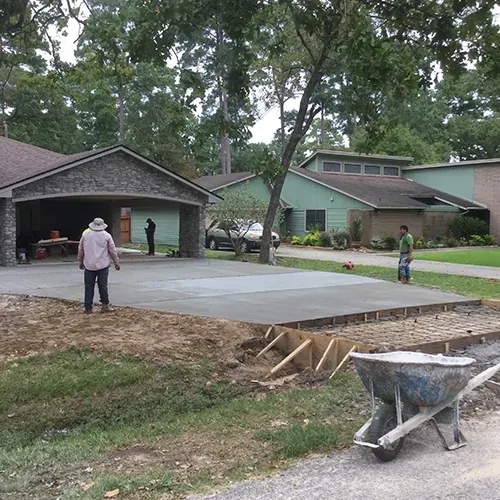 Stone and concrete patio installation in progress with workers and construction materials.