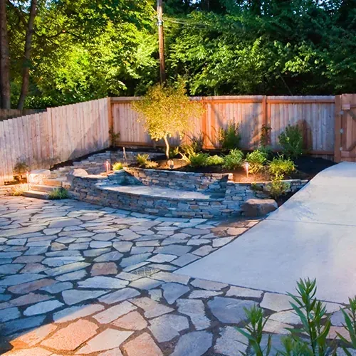 Flagstone patio and walkway with landscape lighting and stone retaining walls.