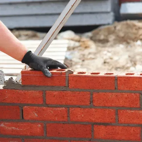 Masonry contractor laying bricks with mortar in Sugar Land, TX
