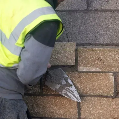 Masonry contractor applying mortar to brick wall, Sugar Land TX.