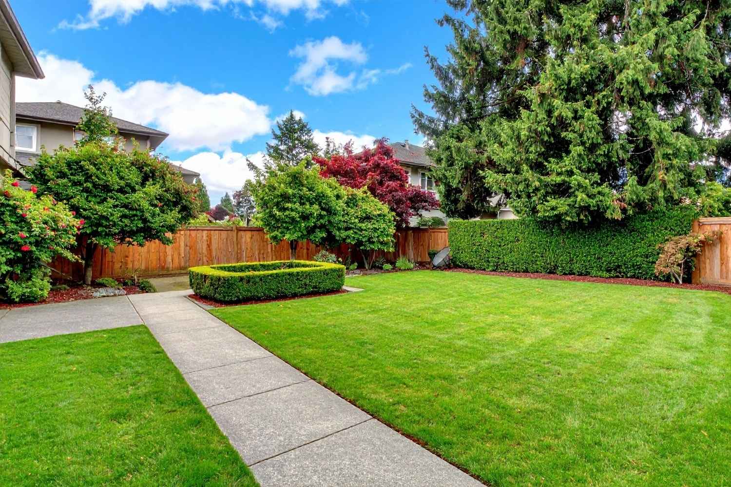 Green lawn in a concrete path and a square shrub with trees in Lititz, PA