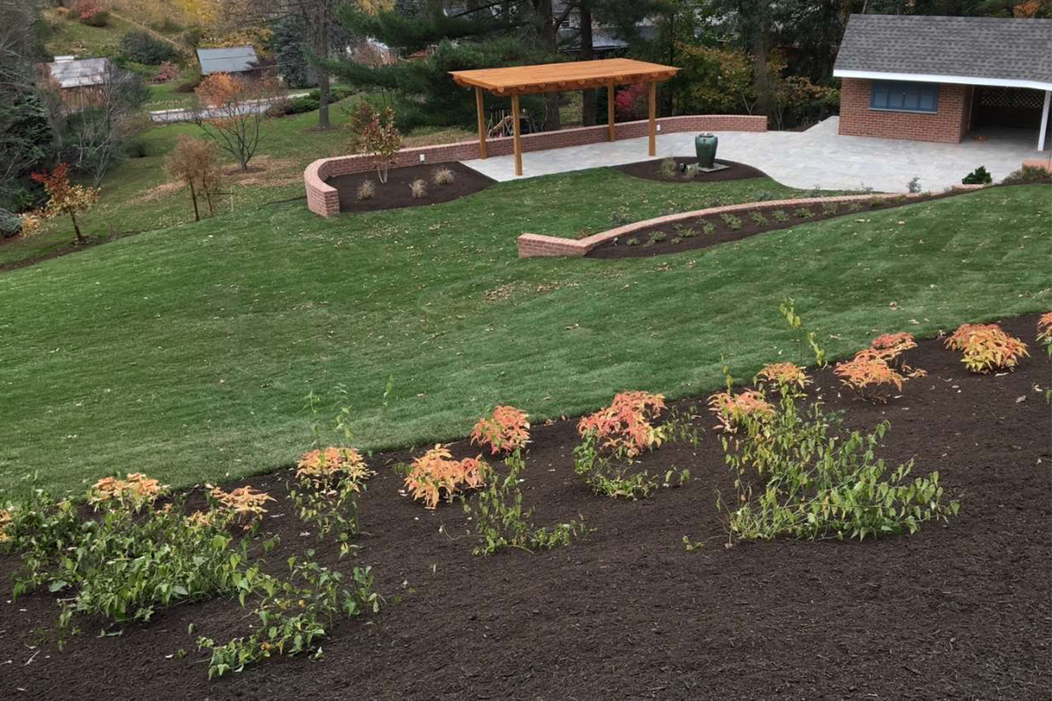 Curved stamped concrete walkway bordered by freshly mulched flower beds, colorful landscaping, and a well-maintained green lawn.