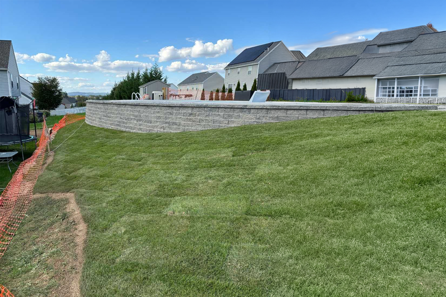 Curved stamped concrete walkway bordered by freshly mulched flower beds, colorful landscaping, and a well-maintained green lawn.