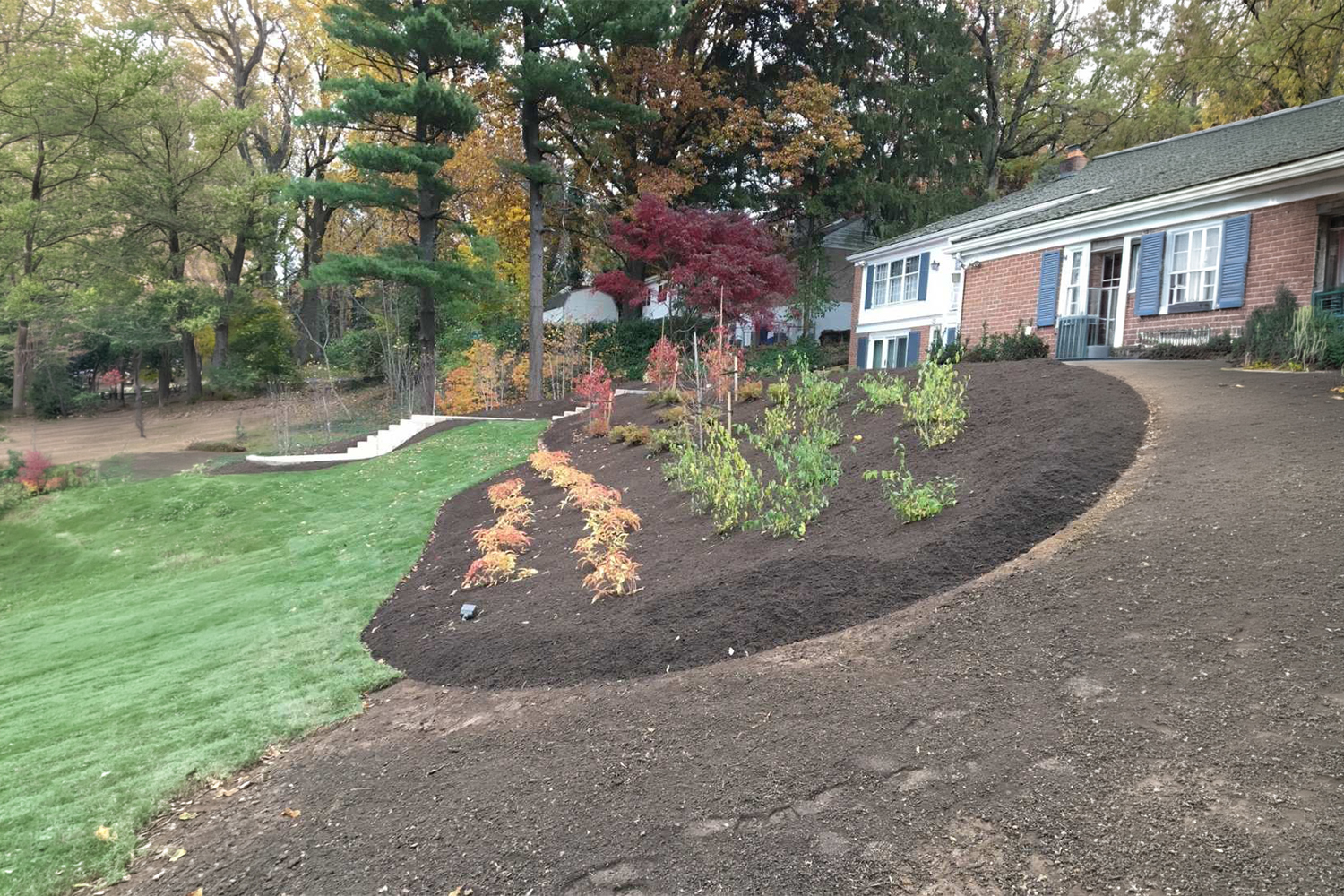 Curved stamped concrete walkway bordered by freshly mulched flower beds, colorful landscaping, and a well-maintained green lawn.