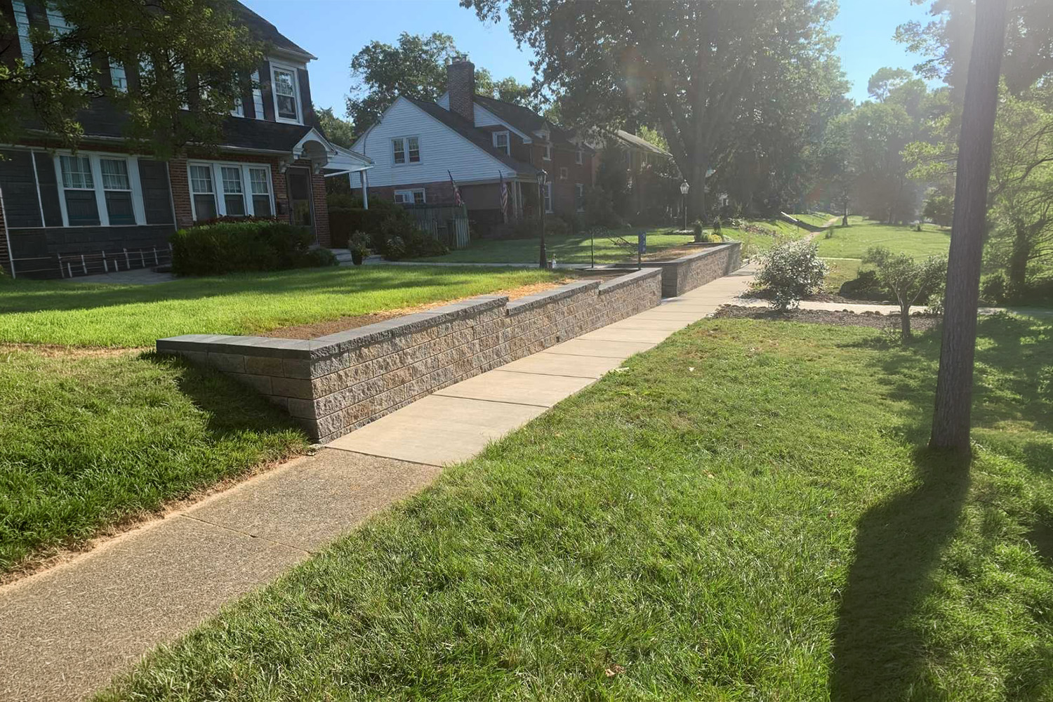 Curved stamped concrete walkway bordered by freshly mulched flower beds, colorful landscaping, and a well-maintained green lawn.