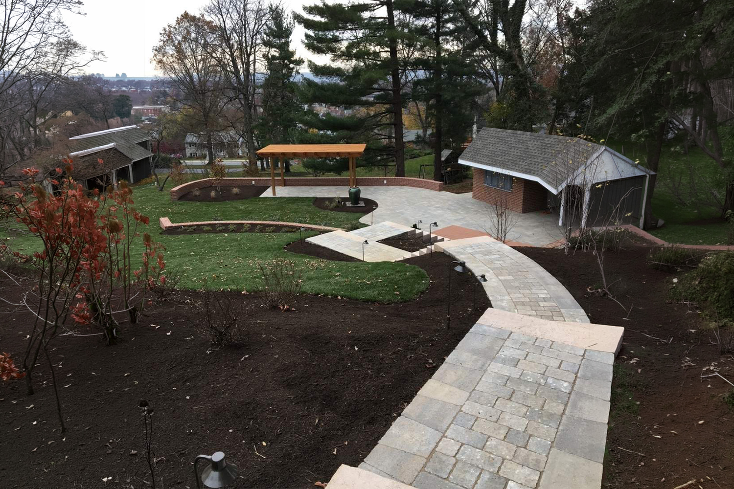 Curved stamped concrete walkway bordered by freshly mulched flower beds, colorful landscaping, and a well-maintained green lawn.