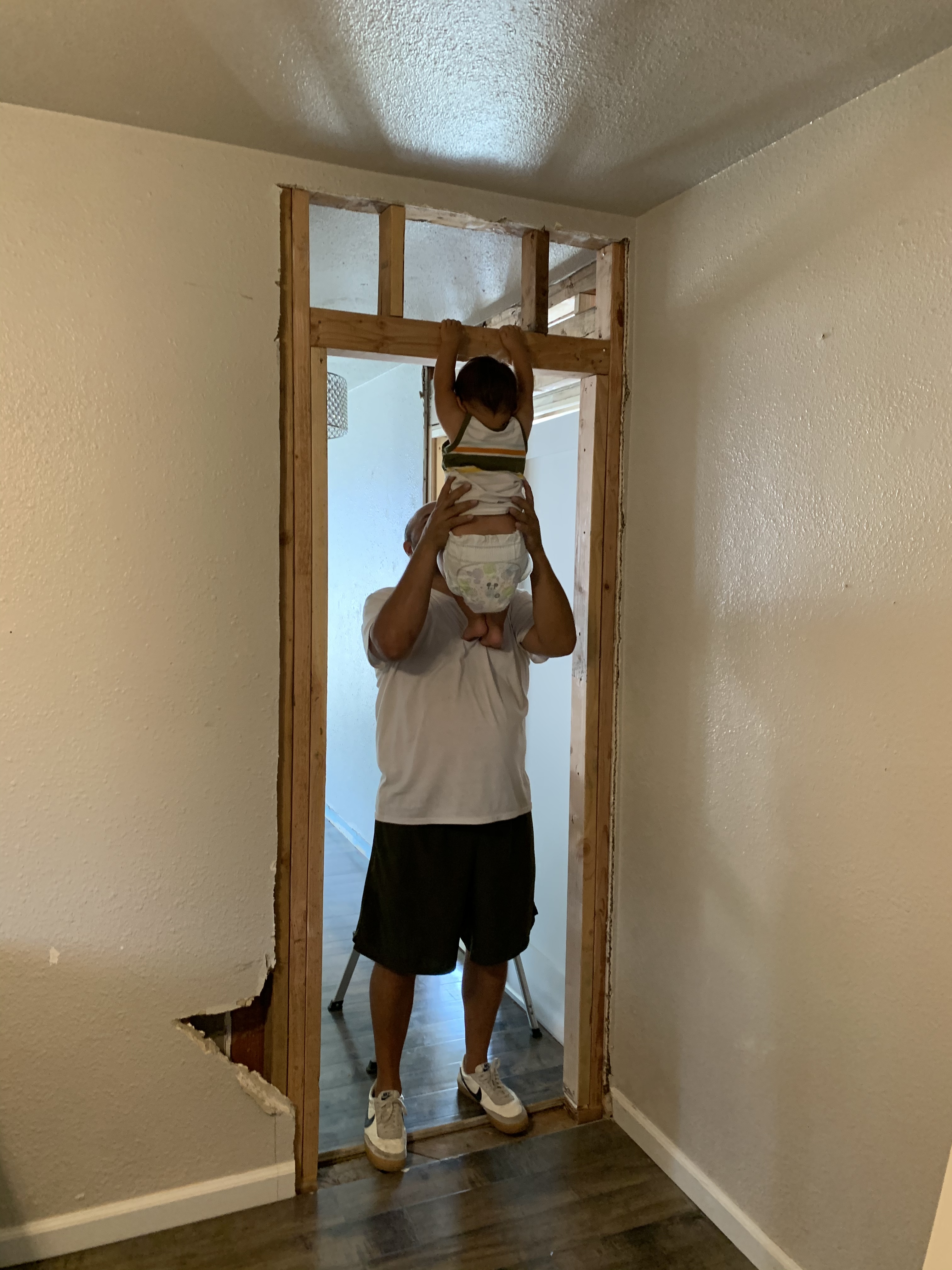 Home renovation in progress with an interior wall opened between two bedrooms and exposed framing visible.