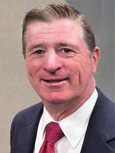 Portrait of Avery Stone, a confident mid-40s female financial advisor in a navy blazer, three-quarter pose, neutral gray background, professional and approachable.