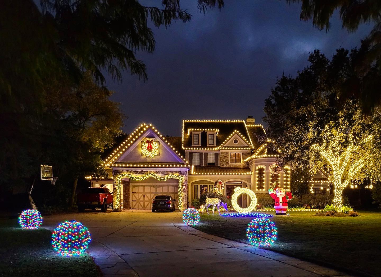 Custom holiday lighting installation with warm white roofline lights and glowing yard spheres.
