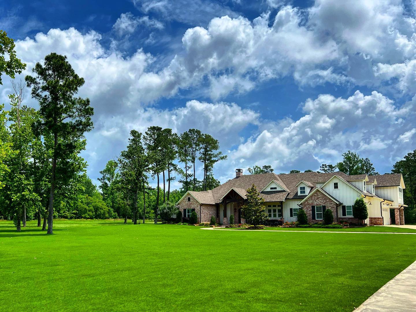 Front yard landscaping featuring manicured lawn, stone borders, and seasonal shrub planting in Katy, TX.