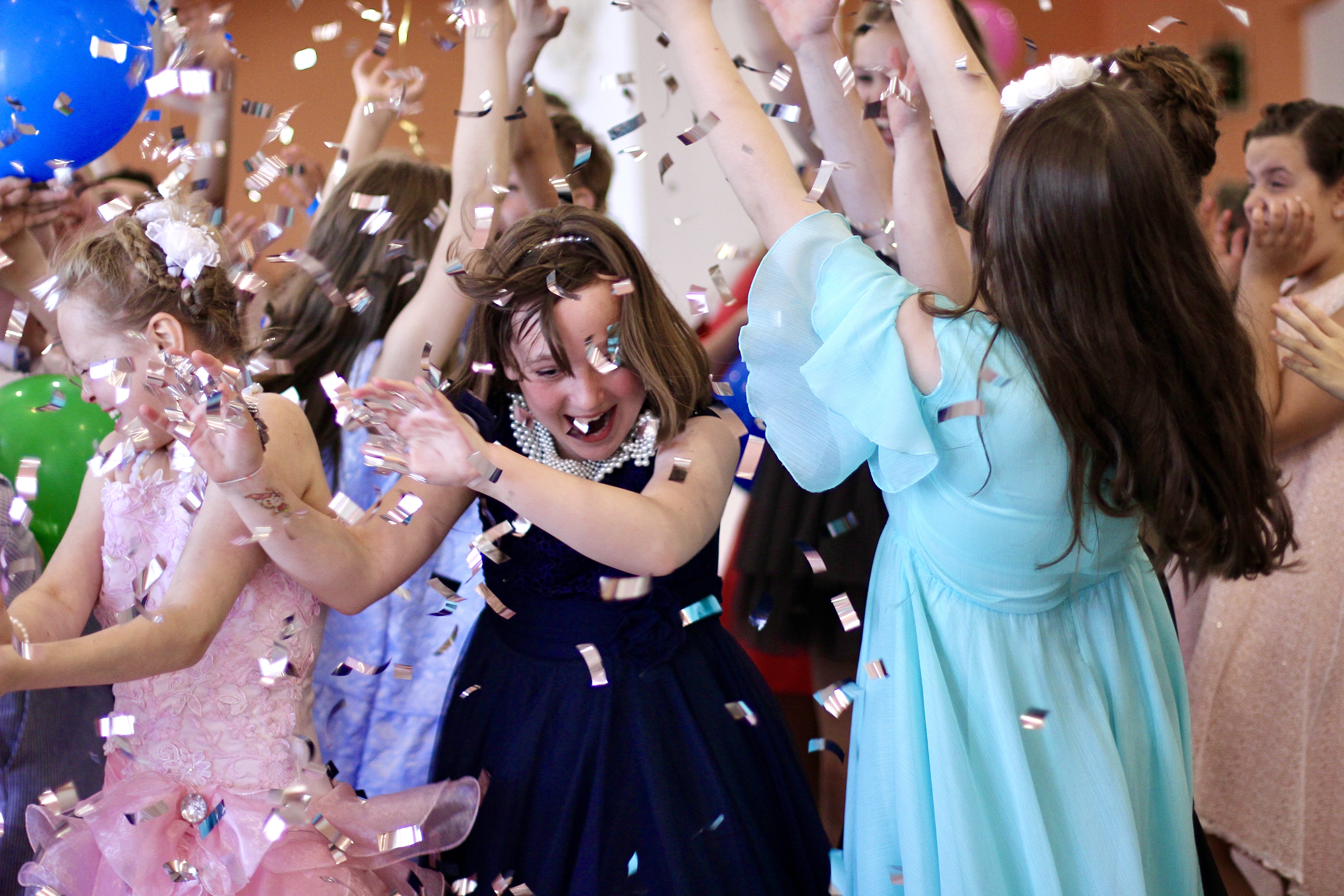Young students celebrating at a school dance event with confetti and formal attire