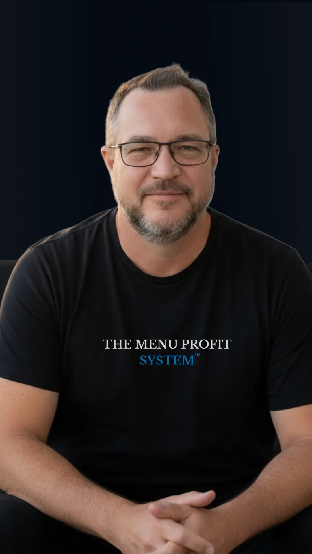 A professional headshot of Paul Spinoglio wearing a black t-shirt with "The Menu Profit System™" logo against a dark background.
