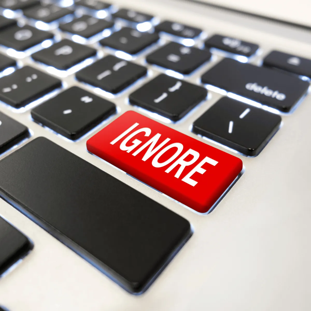 A close-up shot of a laptop keyboard featuring a prominent red key that says "IGNORE" in bold white letters.