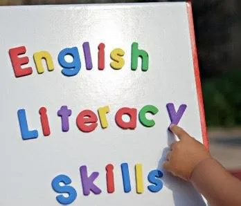 Child writes A in green sand