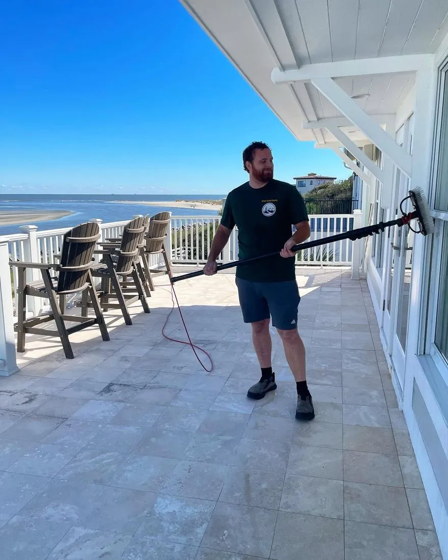 Technician soft washing a covered oceanfront porch and railing, coastal Georgia