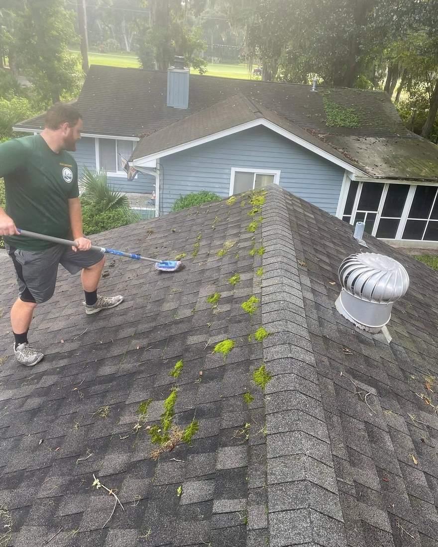 Technician clearing moss and algae from a shingle roof before soft washing, Brunswick GA