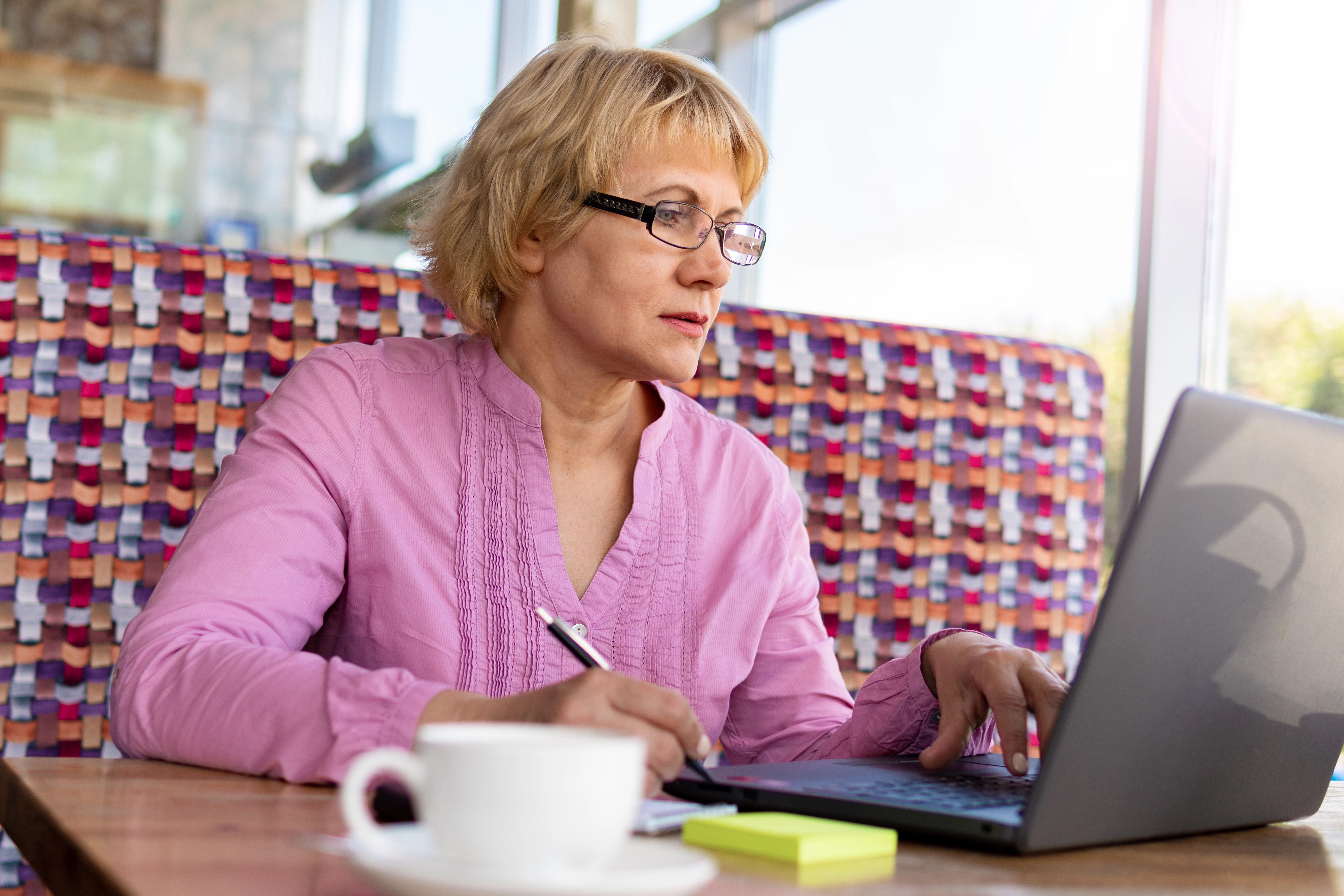 A home office with a laptop open to a webinar screen, a mug of cocoa, and a small holiday plant on the desk. The scene is bright, inviting, and ready for a virtual event, with a window showing a snowy evening outside.