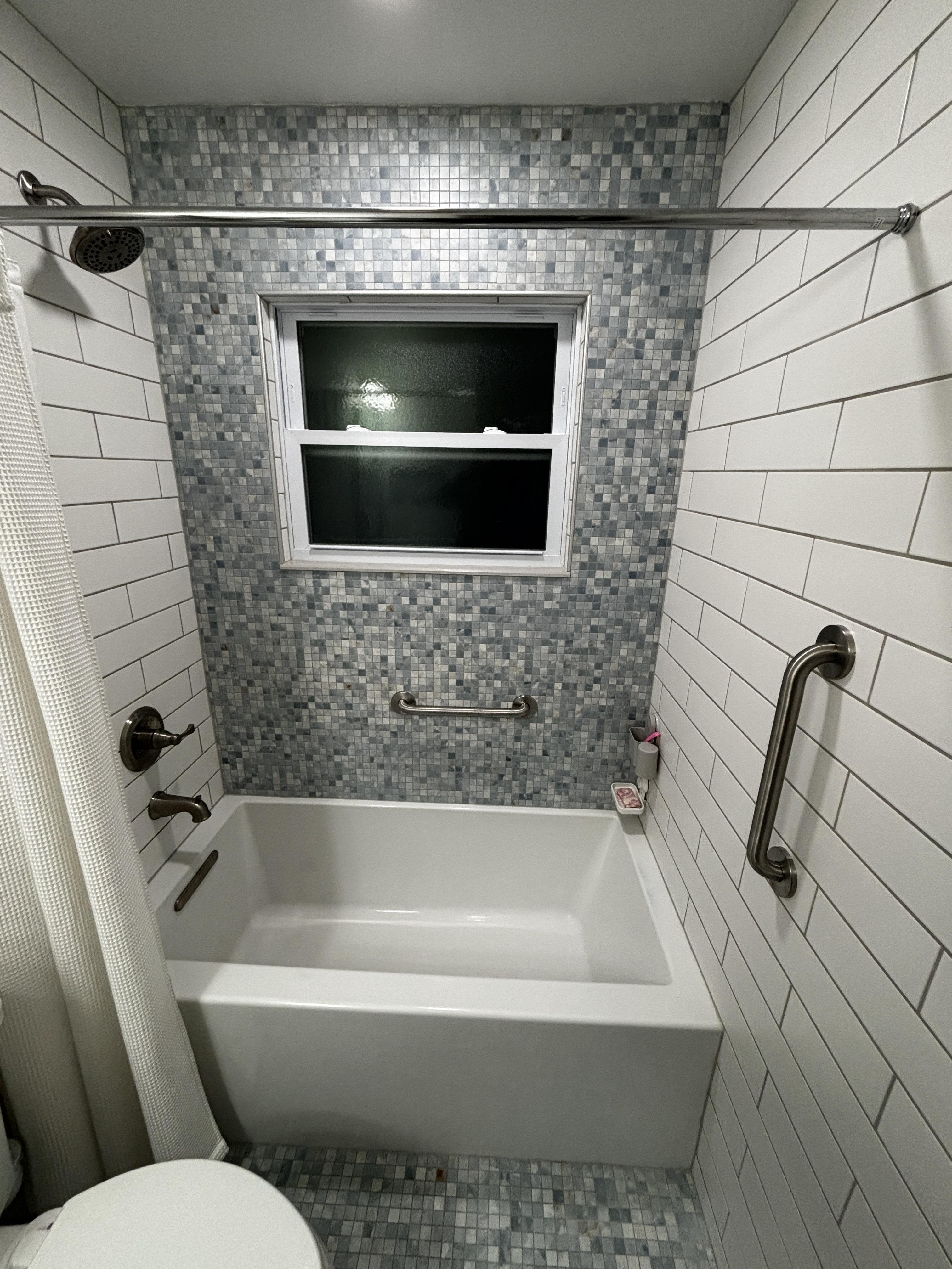 Tiled tub and shower with a horizontal and vertical grab bar installed for fall-prevention safety