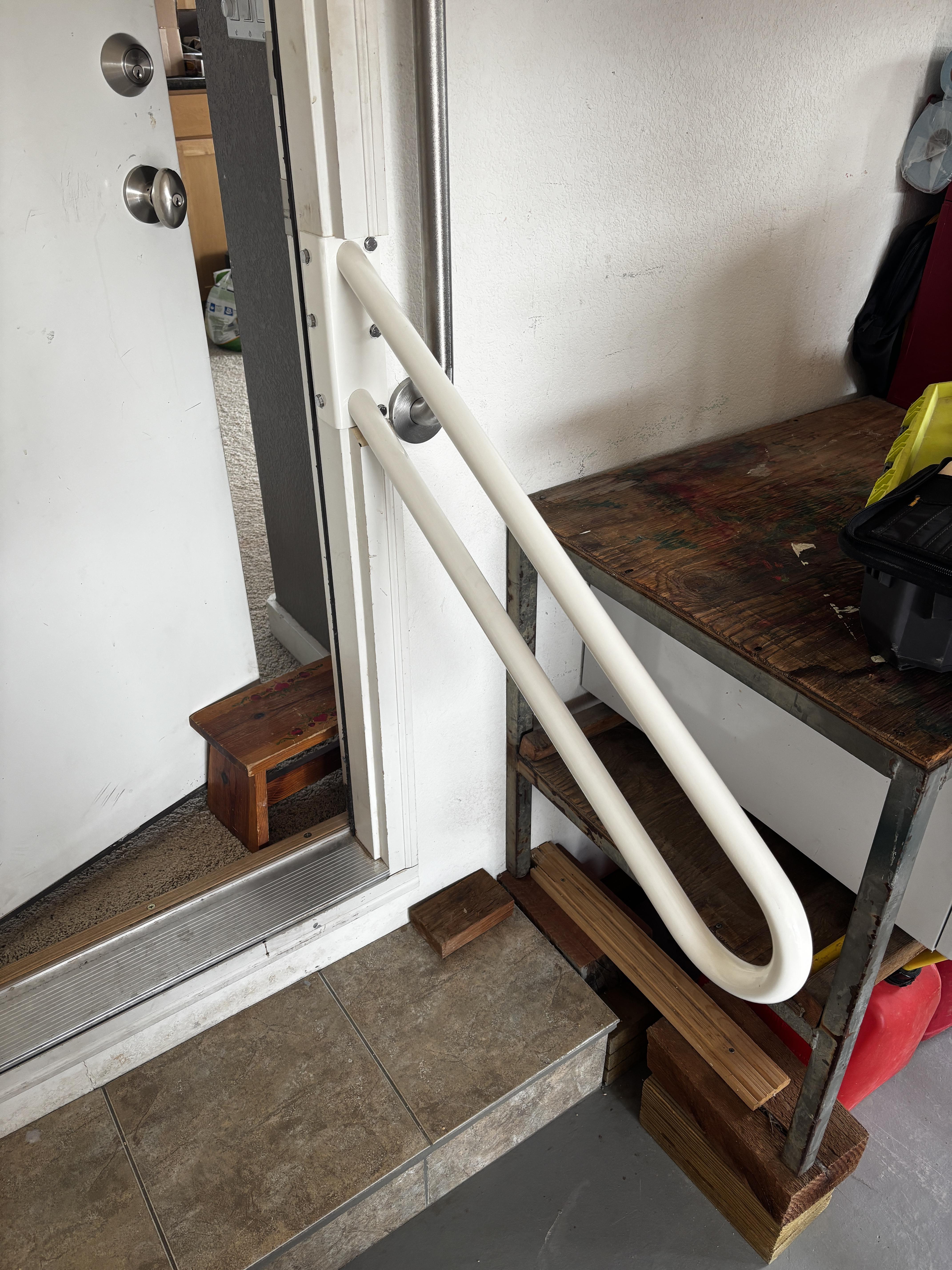 White handrail installed along interior steps at a garage entry doorway