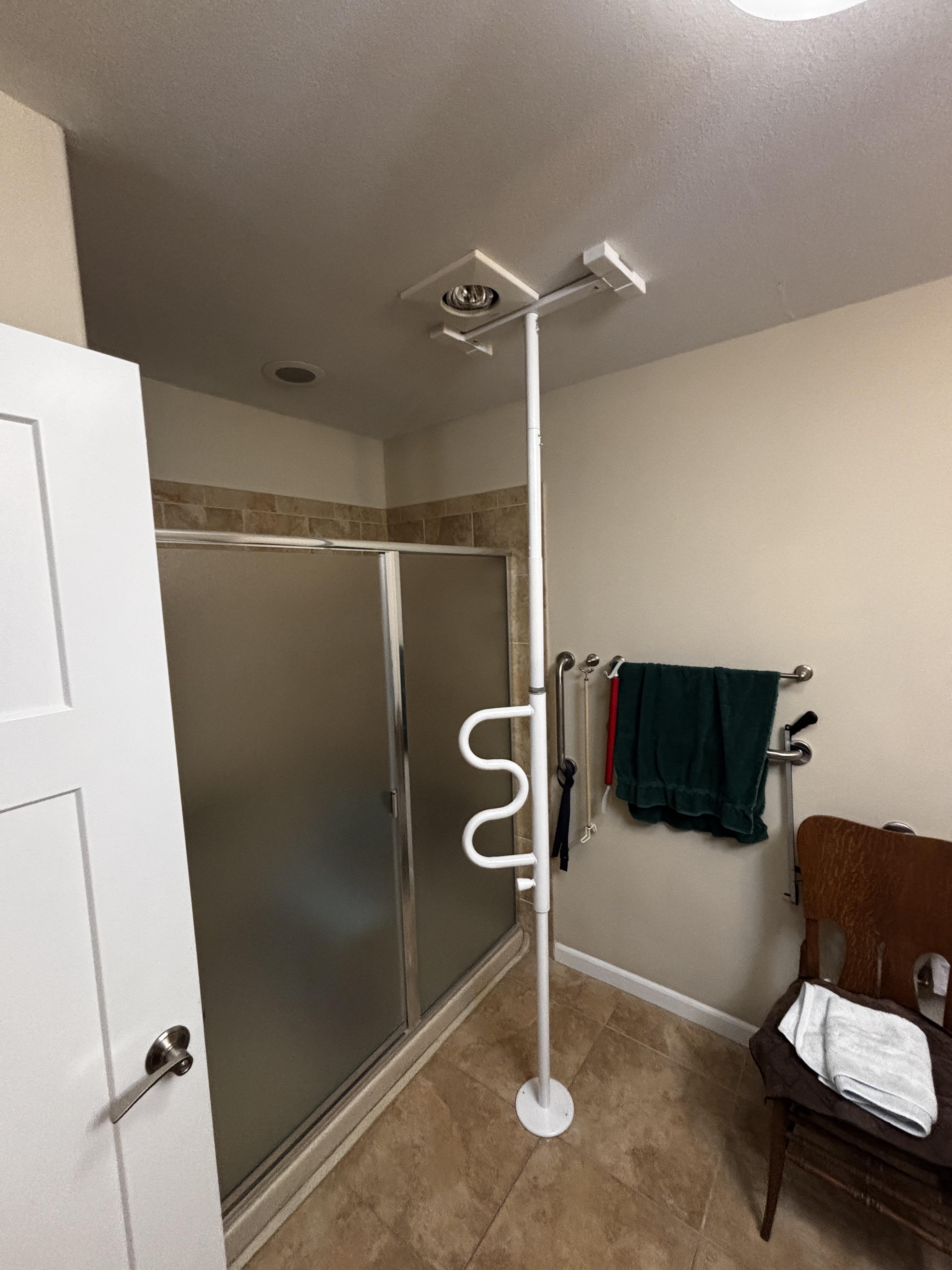 Floor-to-ceiling security pole installed near a shower entrance for added stability