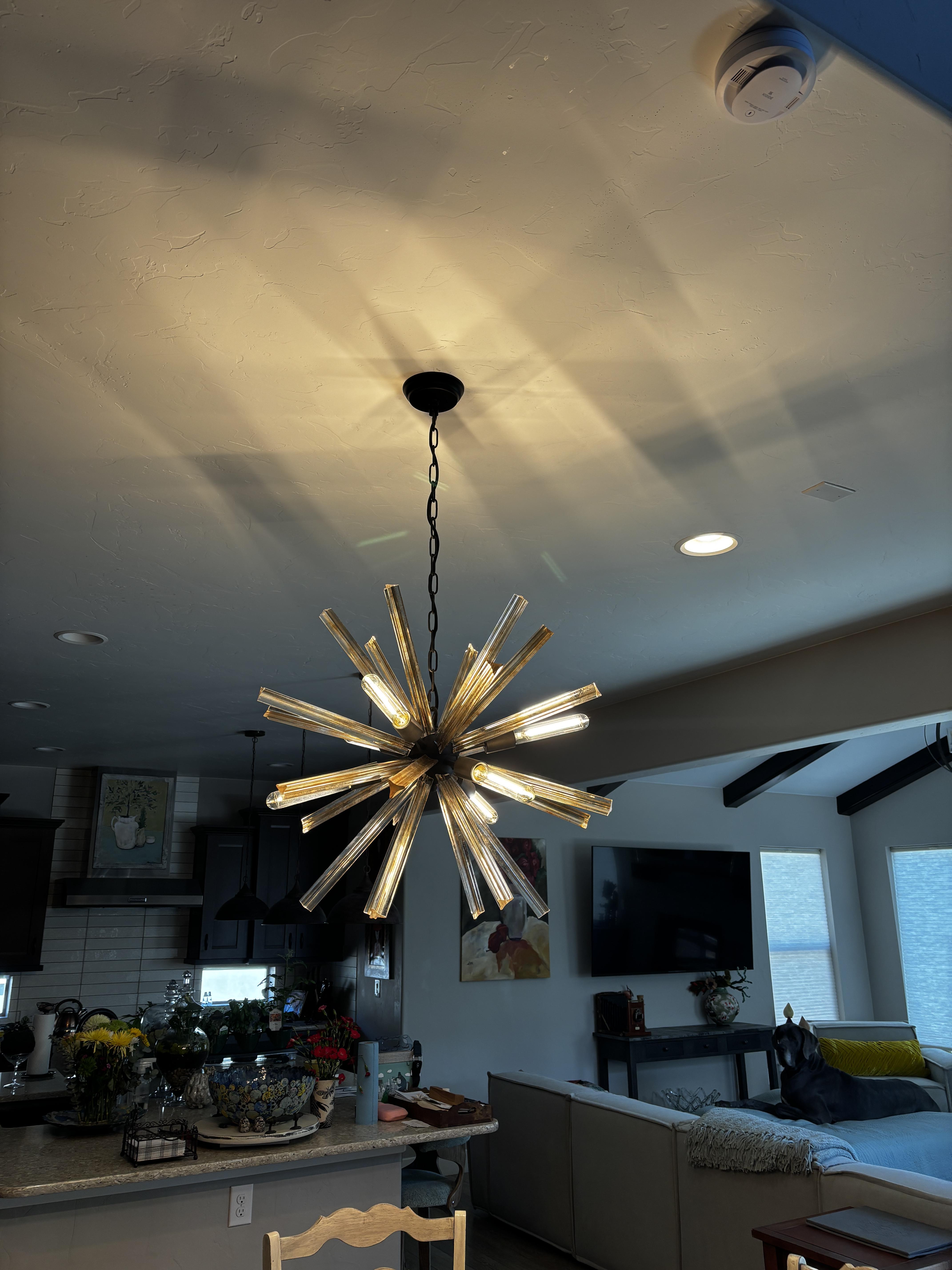 Gold starburst chandelier installed over a kitchen and living area