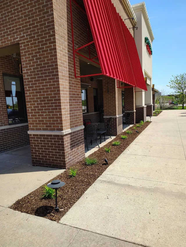 Commercial landscape installation at a restaurant storefront in Oak Park, featuring a long, narrow mulch bed with new, small plantings and landscape lighting along the sidewalk.