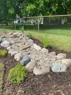 Residential landscape design featuring a decorative rock garden dry creek bed in Oak Park, constructed with large stones and gravel to serve as a drainage solution.