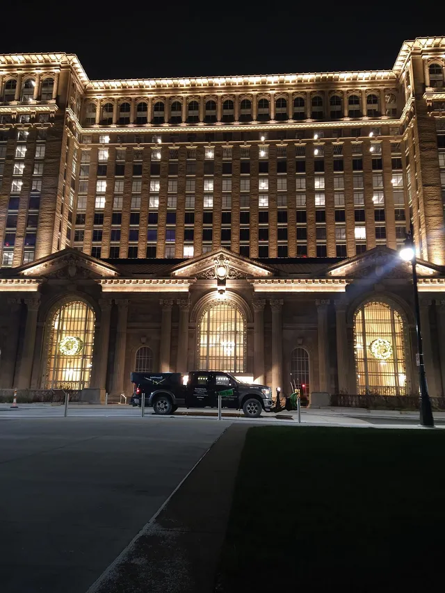 Commercial snow plowing service truck parked in front of a grand, illuminated building at night, showcasing snow removal capabilities for large commercial properties.