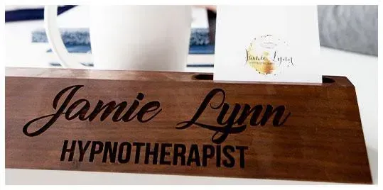 Wooden nameplate with 'Jamie Lynn Hypnotherapist' engraved, with a business card.