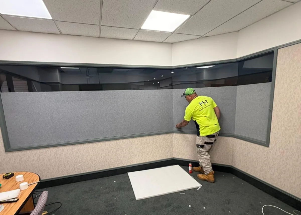 Installer mounting an acoustic sound panel on a ceiling to reduce noise in a commercial space in Dunedin