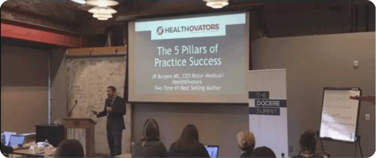 JR Burgess speaking on stage at a seminar