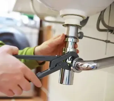 Plumber tightening chrome sink drain fitting during pipe repair in Bexley by Bexley Plumbing Pros