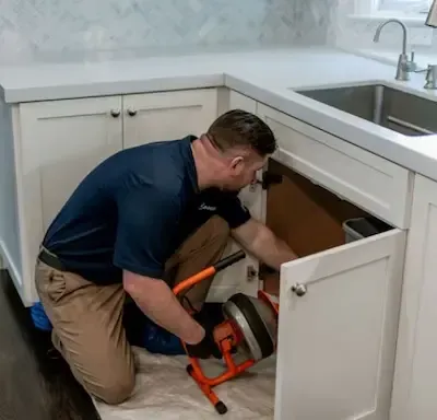 Plumber running electric auger to clear clogged kitchen drain in Bexley by Bexley Plumbing Pros