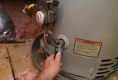 Technician checking water heater connection and pressure valve during service call