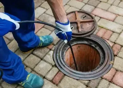 Technician feeding drain snake into open sewer cleanout during backup repair in Bexley