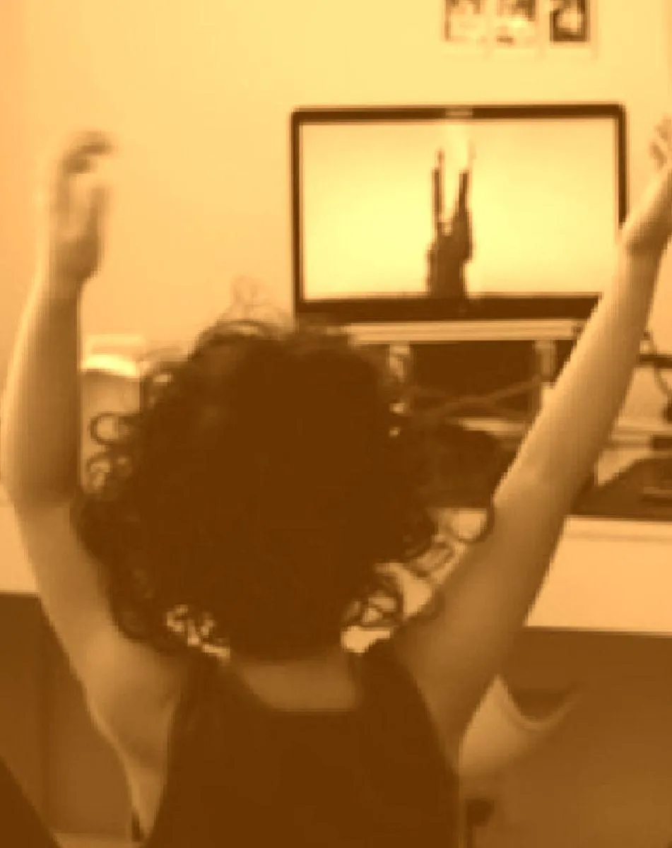 Girl stretches to the side while watching teacher on large screen TV