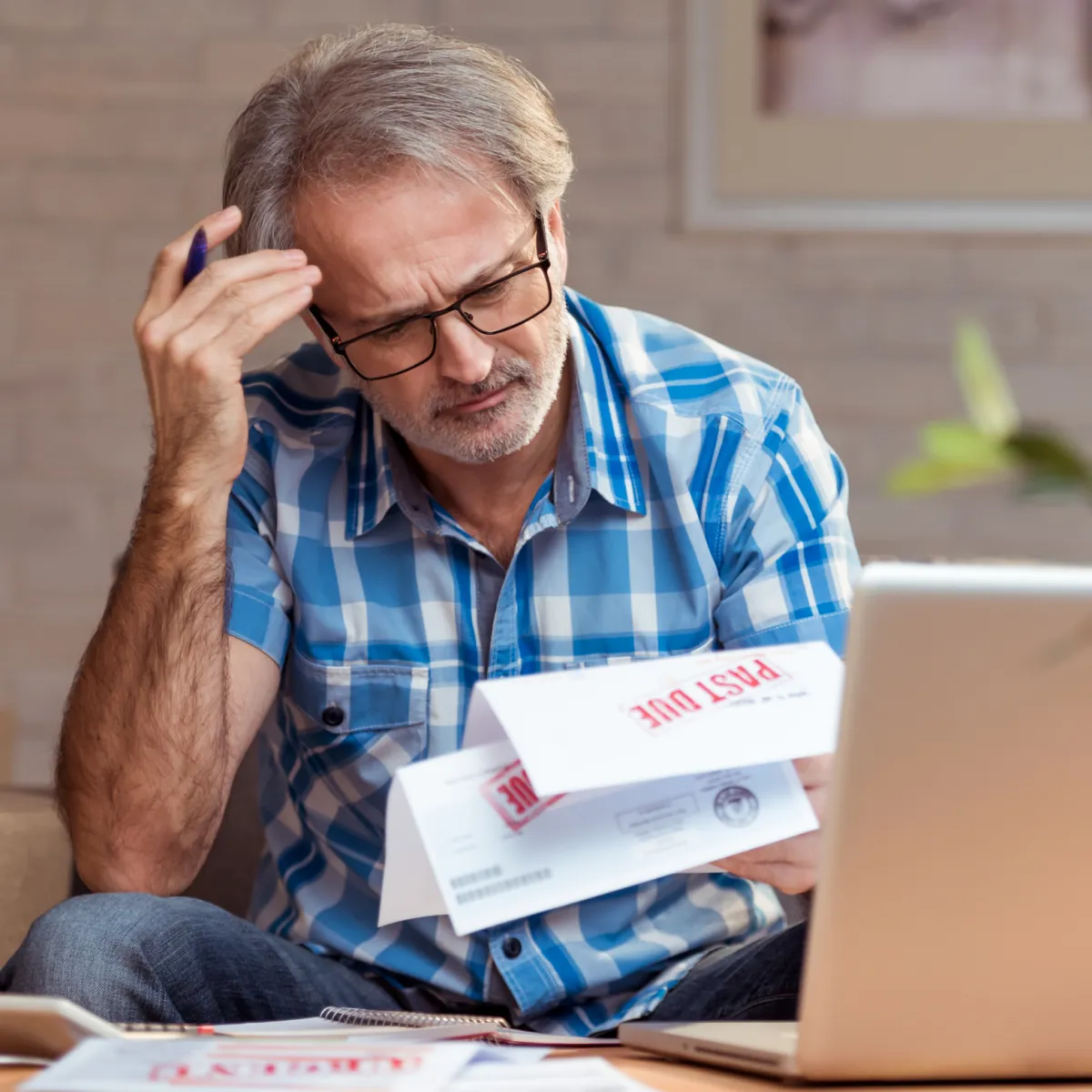 Man reading a past due bill and scratching his head