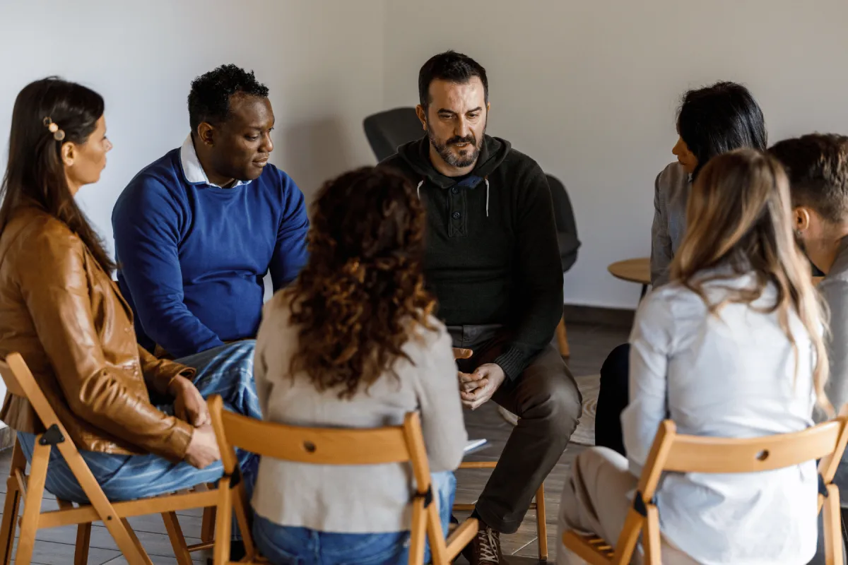 Several people sitting in a circle in a group therapy session