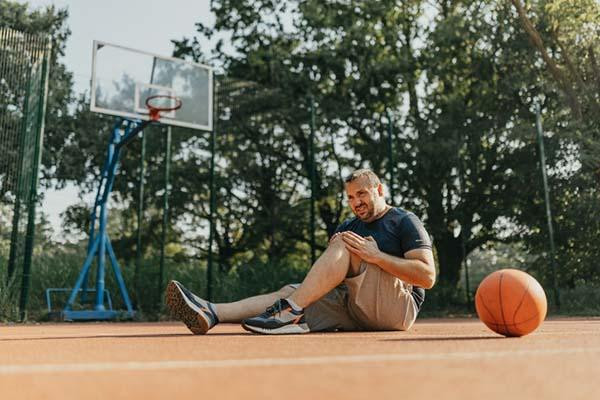 Coach demonstrating a single-leg eccentric tendon-loading exercise with a resistance band in a bright training studio.