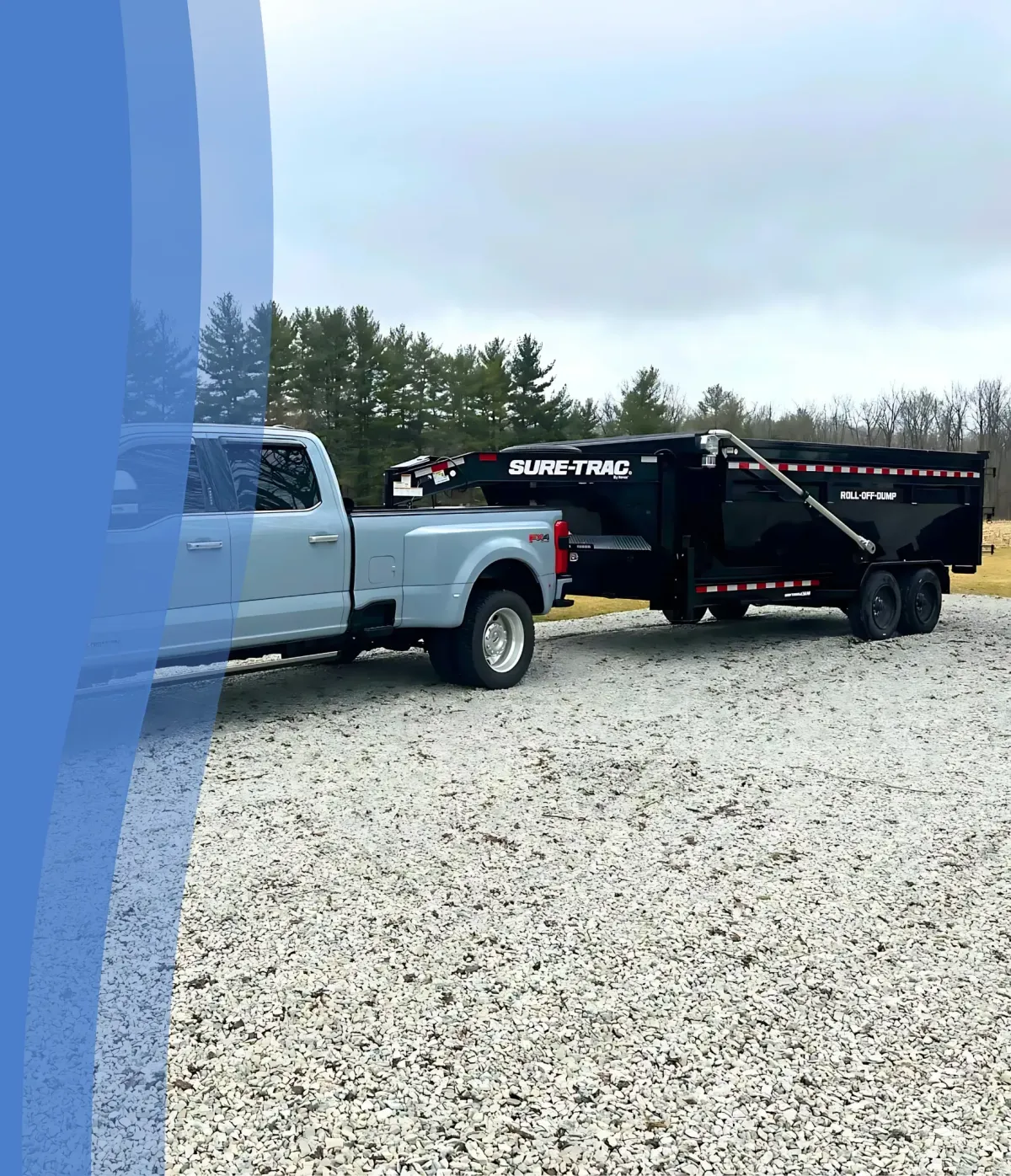 Dumpster Junkies roll-off dump trailer hitched to a white Ford pickup truck on a gravel lot.