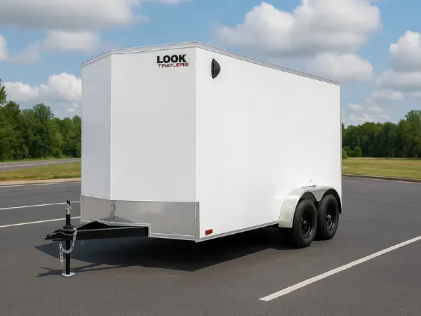 White enclosed Look trailer parked in an empty lot under a sunny sky.