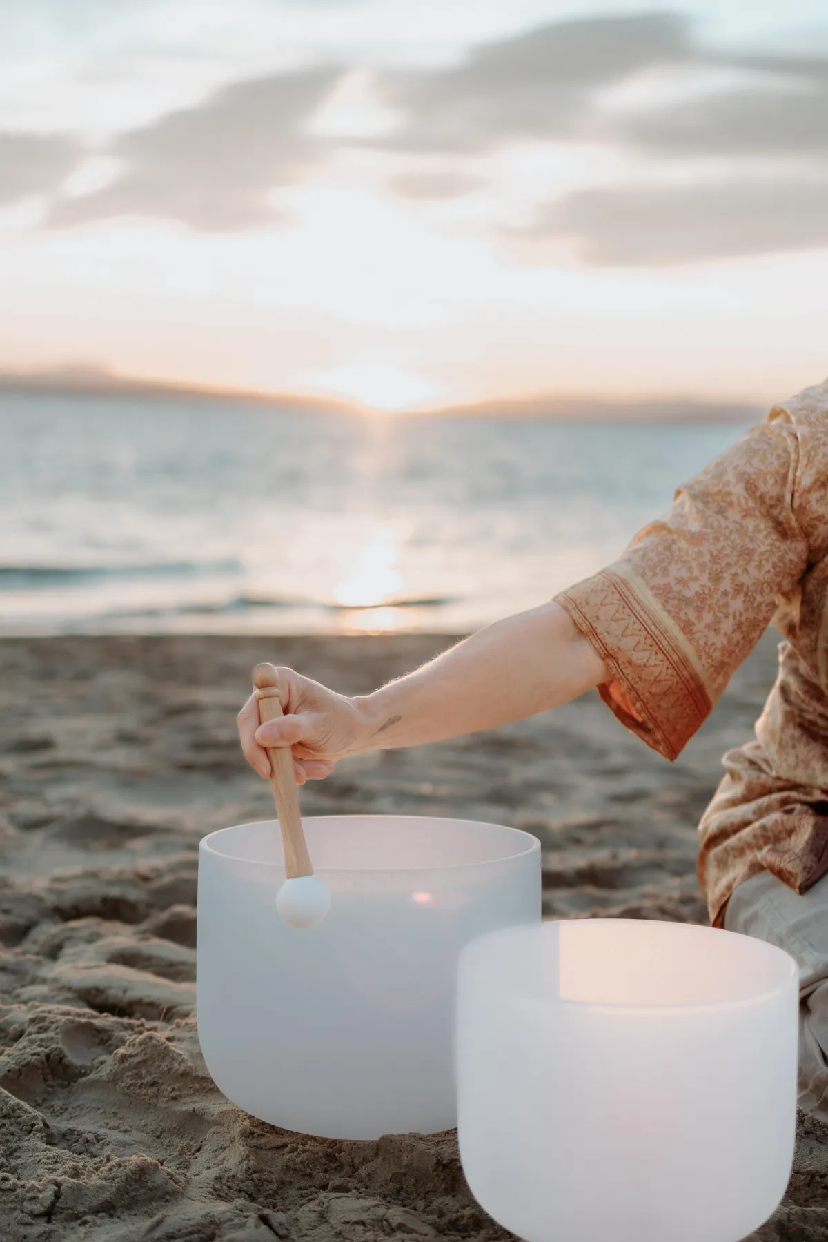 woman playing crystal singing bowls on beach for calm