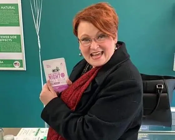 A woman presents a package of pills, symbolizing her dedication to maintaining health and well-being in a vibrant atmosphere