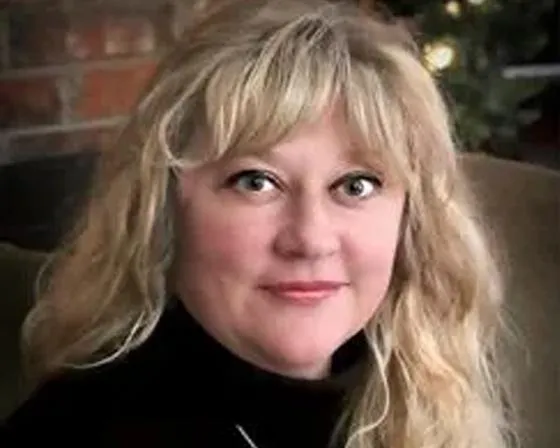 A woman with blonde hair is seated comfortably on a couch, exuding a relaxed and serene demeanor